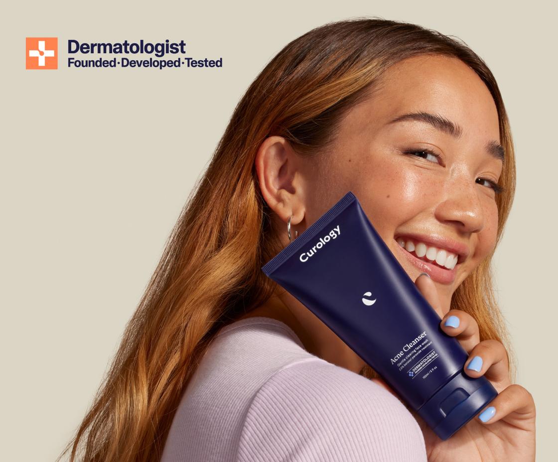 woman holding a bottle of Curology acne cleanser smiling