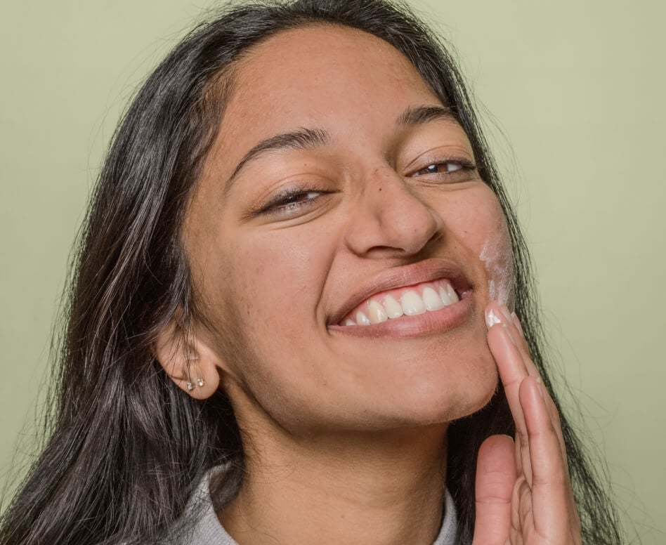 Smiling teen applying Curology to their face